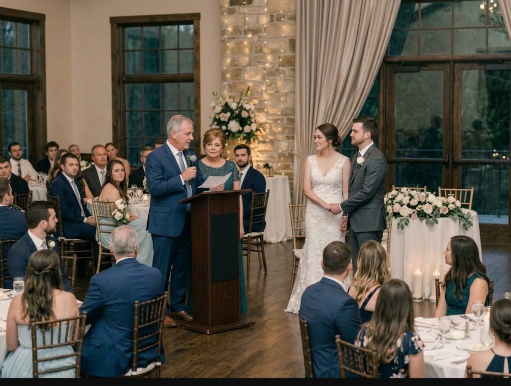 A late-middle-aged couple standing at the podium at a wedding reading a poem to the bride and groom.